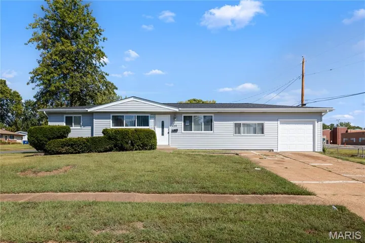 Single story home featuring concrete driveway, a front lawn, and an attached garage