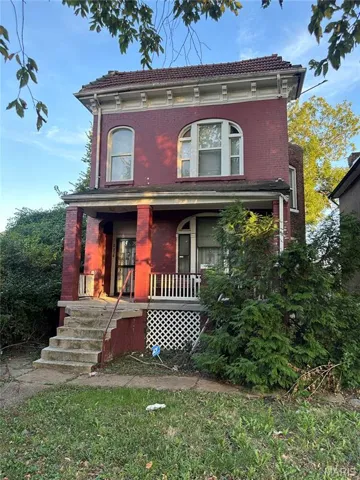 Italianate-style house with a porch, brick siding, and a tile roof