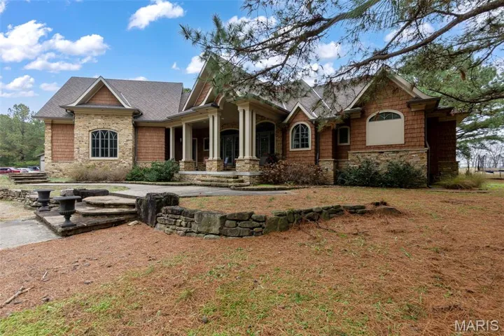Craftsman house featuring stone siding, a porch, and a shingled roof