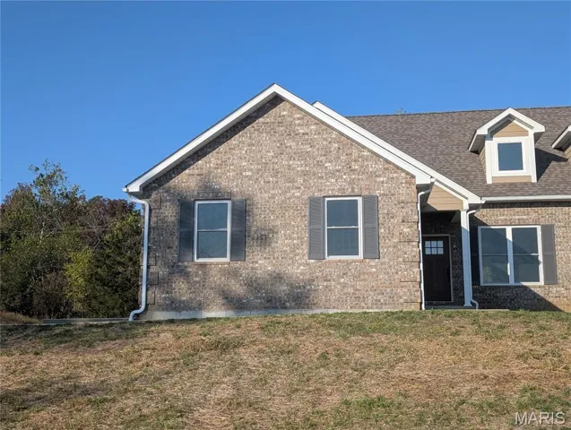 View of front of house with brick siding, a front lawn, and roof with shingles
