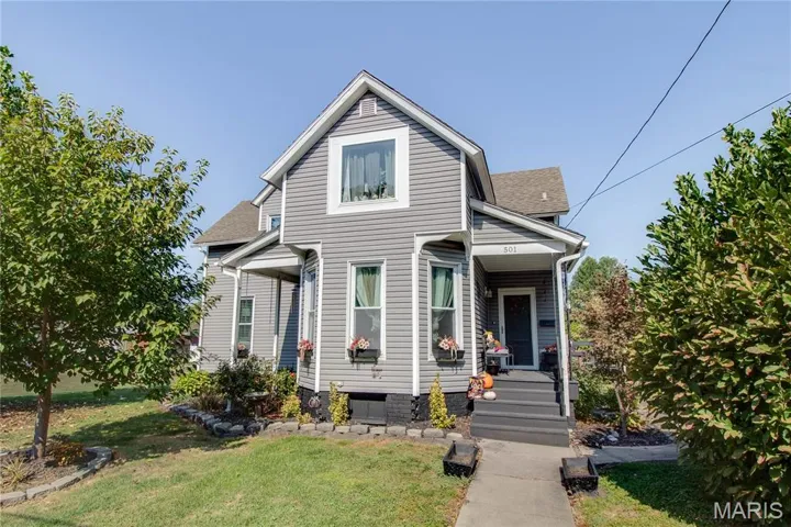 View of front of home with roof with shingles, a front lawn, and a porch