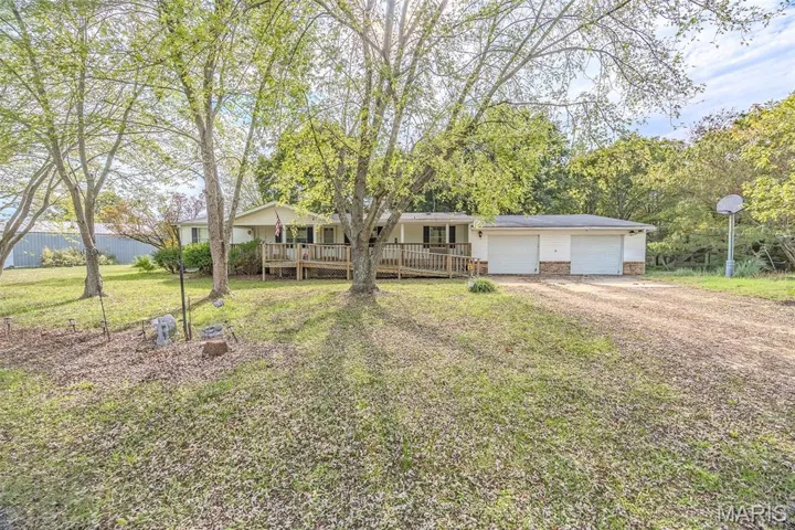 View of front of home with dirt driveway, covered porch, and a garage