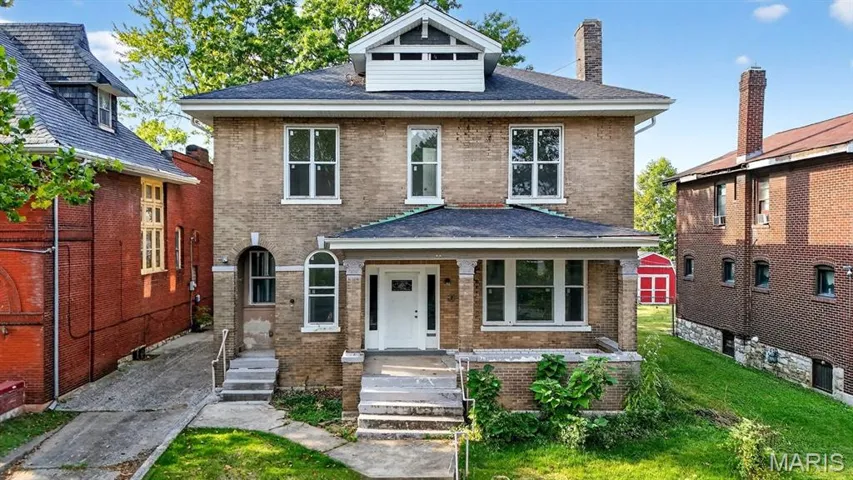 Traditional style home featuring brick siding, a chimney, and a front yard