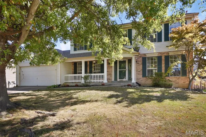 View of front of house featuring covered porch, an attached garage, a front yard, brick siding, and driveway