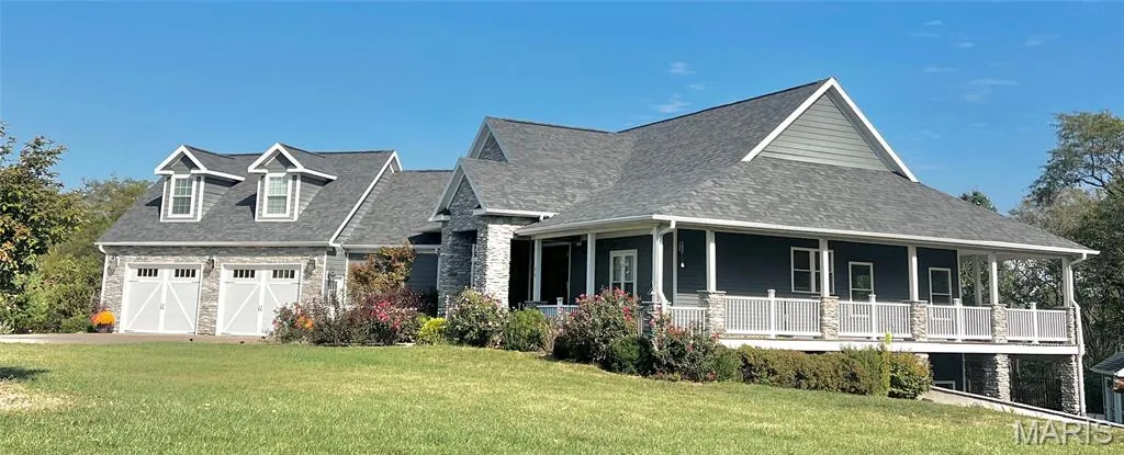 View of front of home with stone siding, a front lawn, a porch, and a shingled roof