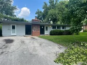 Ranch-style house featuring a chimney, a front yard, and driveway