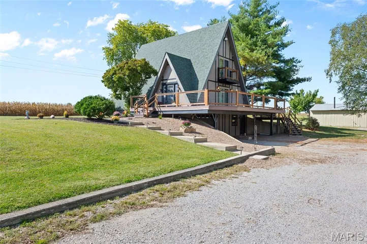 View of front of house with stairs, a wooden deck, a front lawn, and roof with shingles