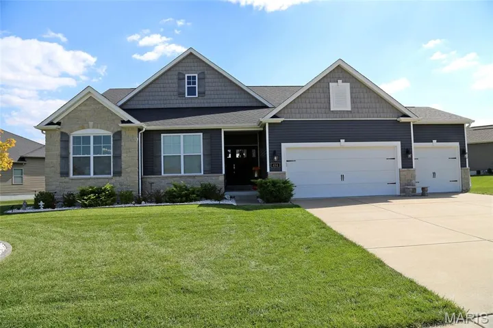 Craftsman house featuring stone siding, a front lawn, a shingled roof, and concrete driveway