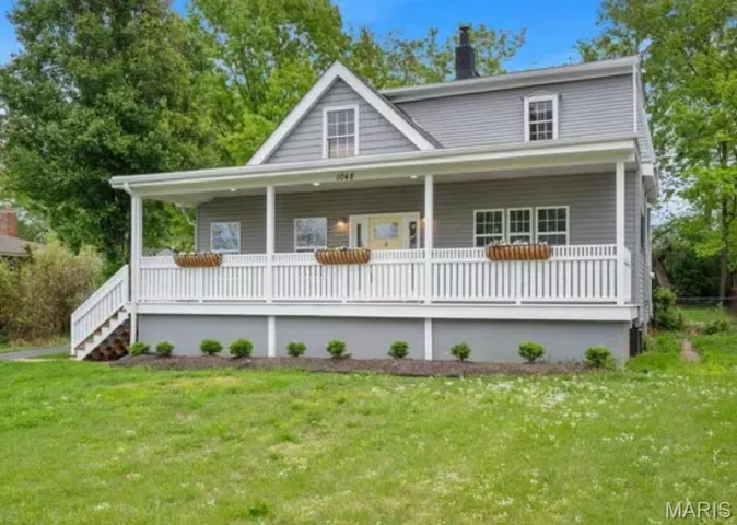 View of front of home with a porch, a front lawn, a chimney, and stairs