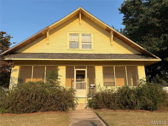 View of front of home with covered porch, a front yard, and roof with shingles