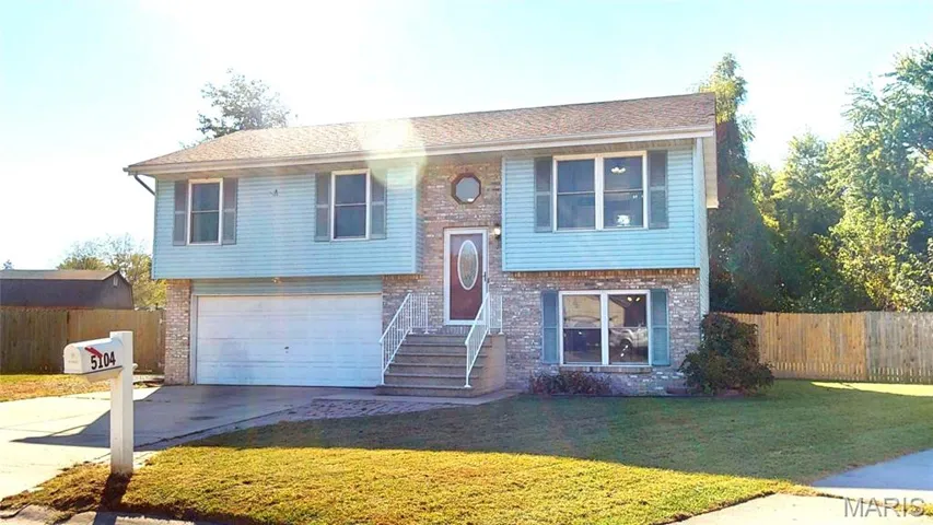 Bi-level home with brick siding, driveway, and an attached garage