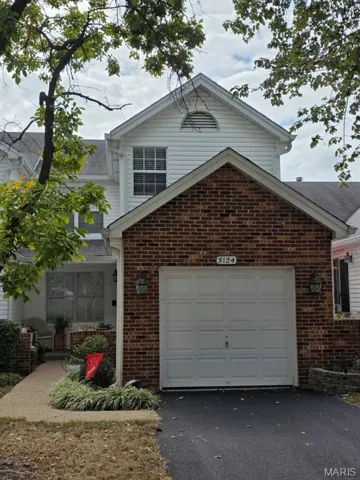 Traditional-style house featuring brick siding, a garage, asphalt driveway, and a sunroom