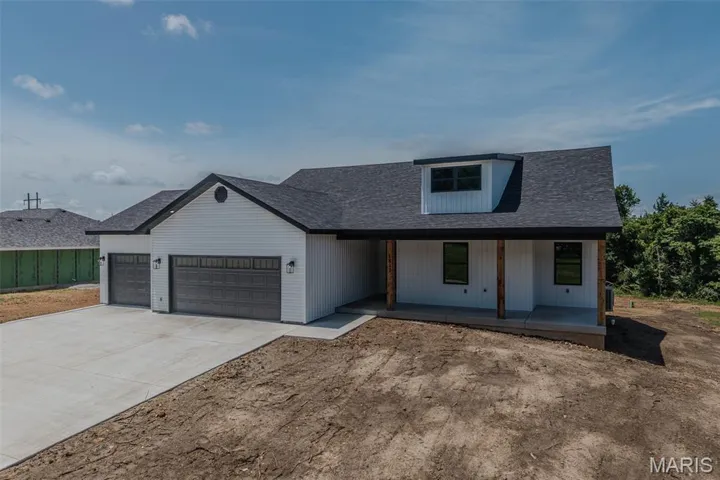 Modern inspired farmhouse featuring a garage, a porch, driveway, and roof with shingles