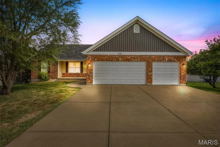 Ranch-style home featuring a lawn, driveway, covered porch, board and batten siding, and a garage