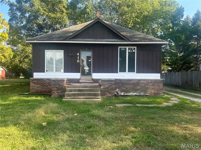 View of front of house with board and batten siding, a chimney, a shingled roof, and entry steps