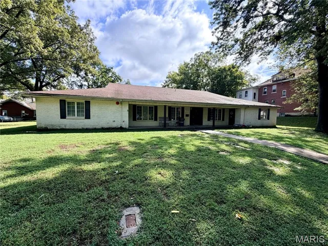 Ranch-style home with brick siding, a front yard, and covered porch