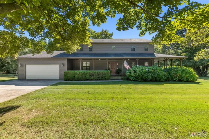 View of front facade featuring covered porch, concrete driveway, and a front lawn