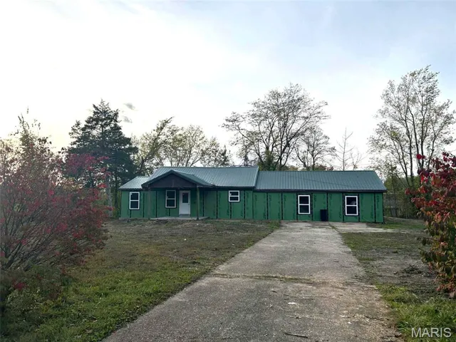 Single story home featuring a metal roof, driveway, and a front yard