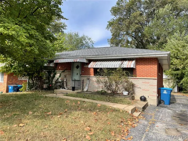 View of front of property with a front yard, brick siding, and roof with shingles
