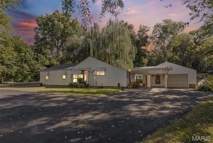 Ranch-style home featuring a garage, a carport, driveway, and a yard