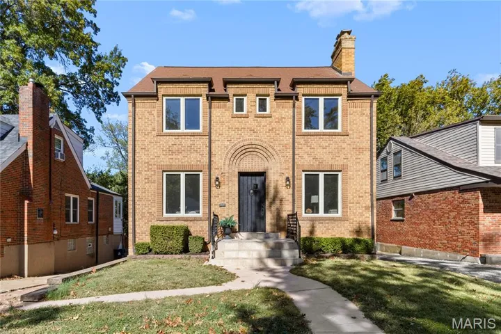 View of front of house featuring brick siding, a front yard, a chimney, and roof with shingles