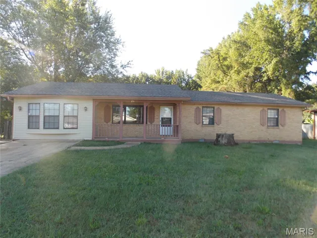 Single story home featuring a front yard, brick siding, a porch, and concrete driveway