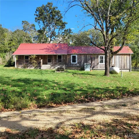 Rear view of house featuring a lawn, a metal roof, and covered porch