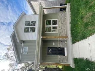 View of front of house featuring board and batten siding, a porch, stone siding, and a front lawn