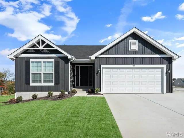 View of front of home featuring a garage, driveway, and a front yard