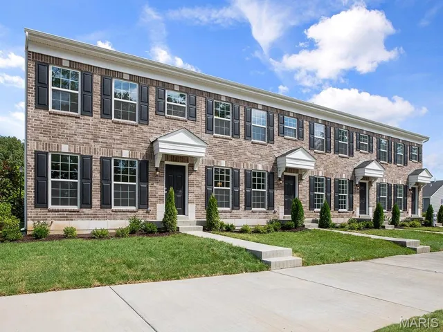 Colonial-style house featuring brick siding and a front lawn