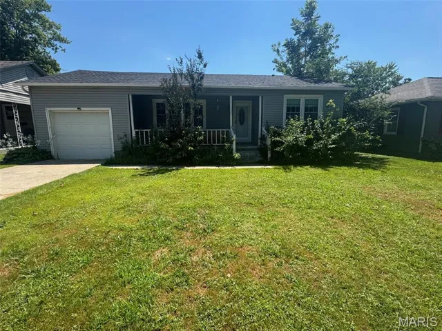 Single story home featuring a porch, a front lawn, an attached garage, and driveway