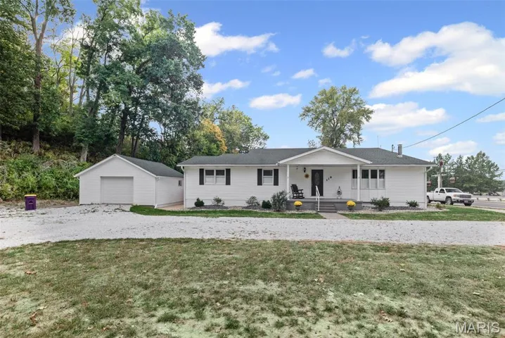 Ranch-style house featuring an outdoor structure, a porch, a detached garage, a front yard, and driveway
