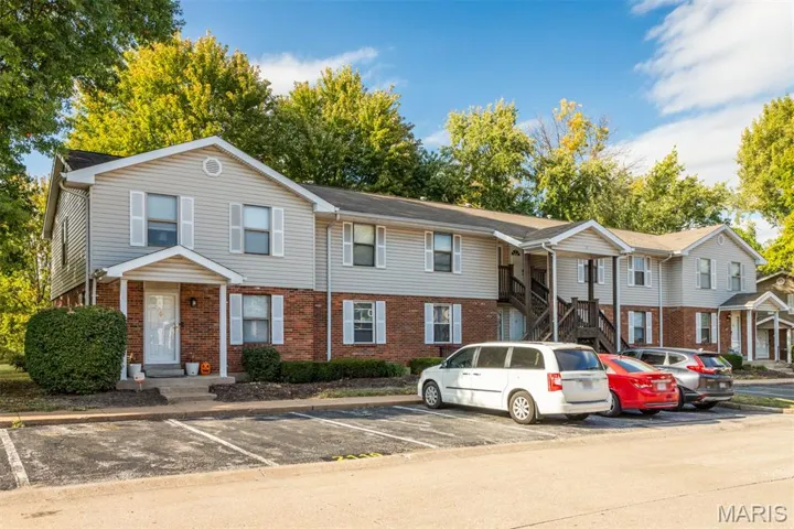 View of front of home featuring brick siding, uncovered parking, and stairs