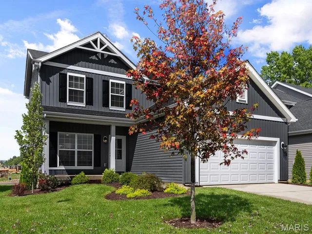 View of front of home featuring a front lawn, concrete driveway, a porch, and board and batten siding