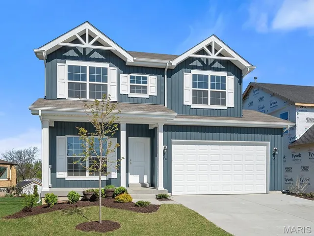 View of front of home with concrete driveway, an attached garage, a front yard, a shingled roof, and covered porch
