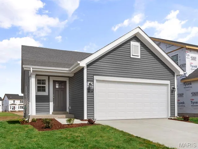 View of front of property with concrete driveway, an attached garage, and a front lawn