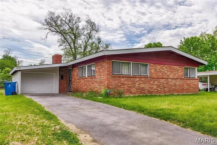 Ranch-style home with brick siding, a chimney, and a front yard