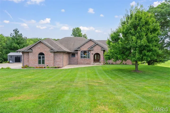 View of front of property with brick siding, a shingled roof, and a front yard