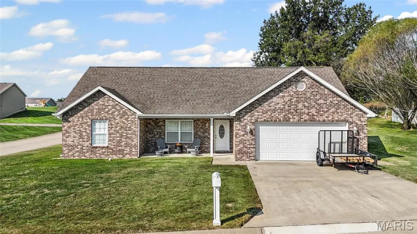 View of front of property with a shingled roof, covered porch, brick siding, driveway, and a front yard