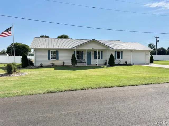 Ranch-style home with covered porch, a metal roof, driveway, and a garage