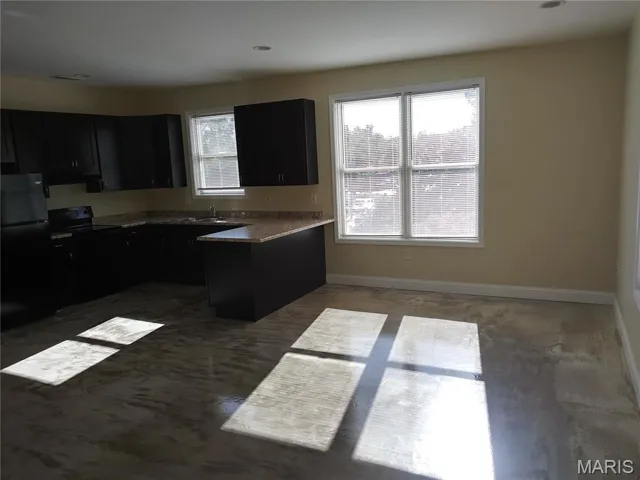 Kitchen with black appliances, dark cabinets, a peninsula, and under cabinet range hood