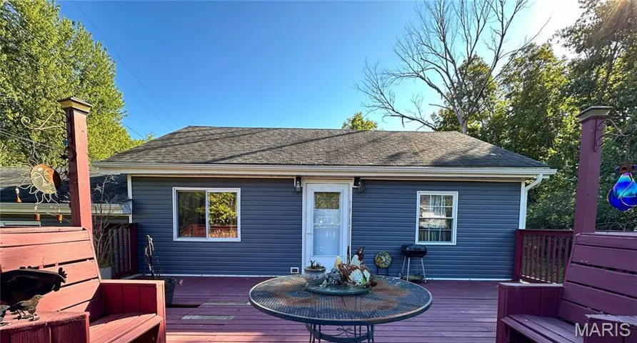Back of property with a deck and roof with shingles