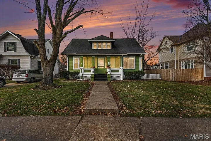 Bungalow-style home featuring a chimney, a front lawn, covered porch, and a shingled roof