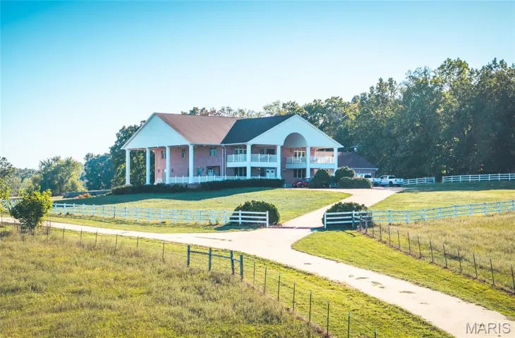Greek revival inspired property featuring a front lawn, a porch, and a view of countryside