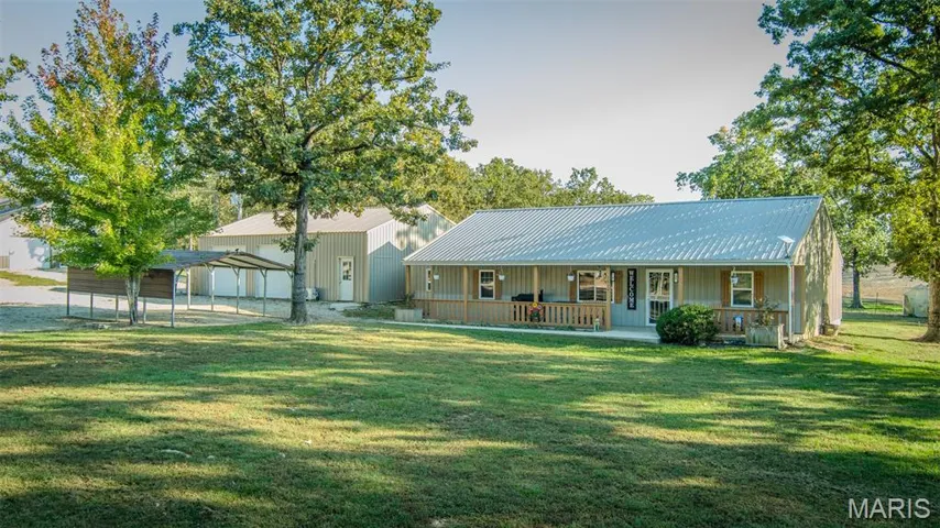 Rear view of property featuring a yard, covered porch, a metal roof, and board and batten siding