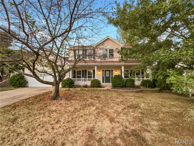 Traditional-style house featuring a porch, a garage, a front yard, and driveway