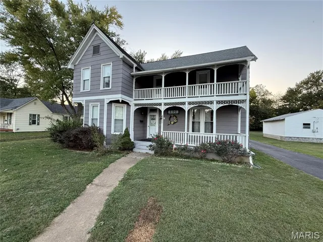 View of front of property with a porch, a yard, and roof with shingles