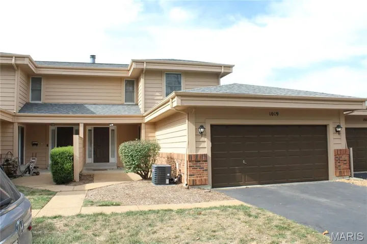 View of front of house featuring brick siding, a porch, driveway, roof with shingles, and an attached garage