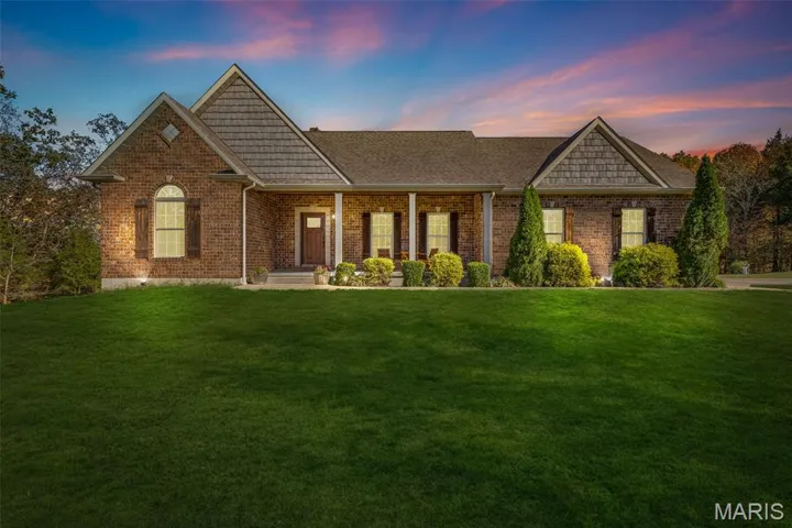 View of front of house with a porch, a lawn, brick siding, and a shingled roof