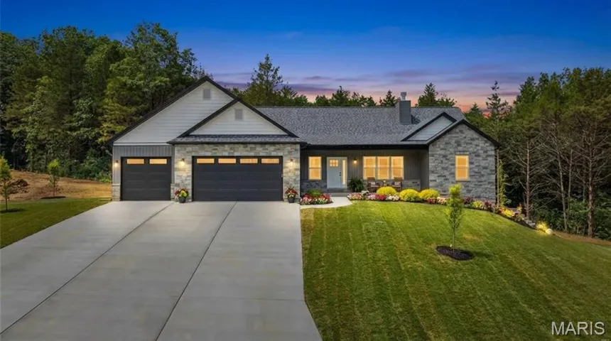 View of front of home with stone siding, an attached garage, a lawn, and driveway